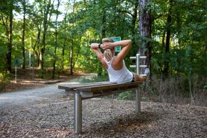 Frau mach Sit-Ups auf einer Bank im Wald