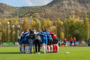 Fußballfrauen stehen in einem engen Kreis auf grünen Rasen