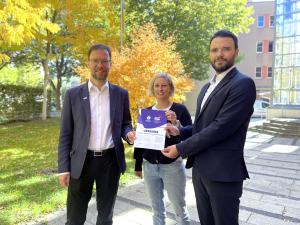 Drei Personen mit Ernennungsurkunde für das Host Town Program