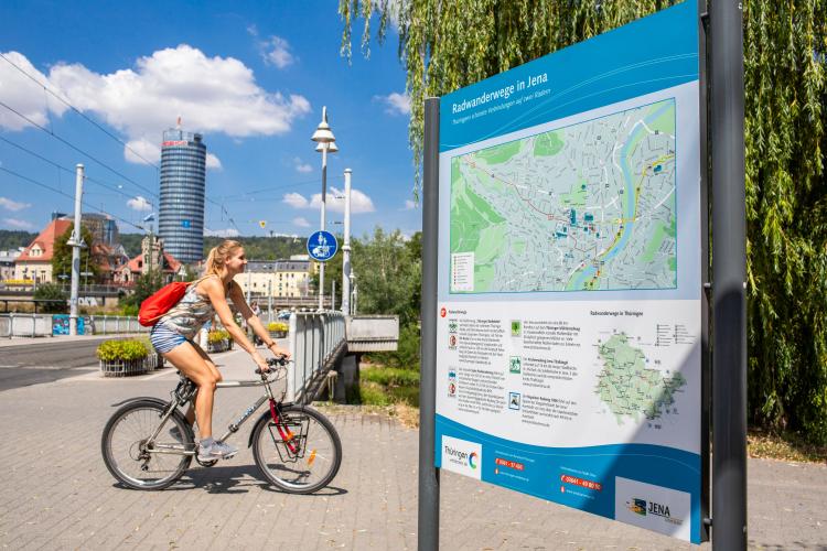 Radfahrerin in Jena vor Schild Radwanderwege in Jena