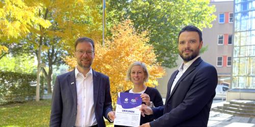 Drei Personen mit Ernennungsurkunde für das Host Town Program