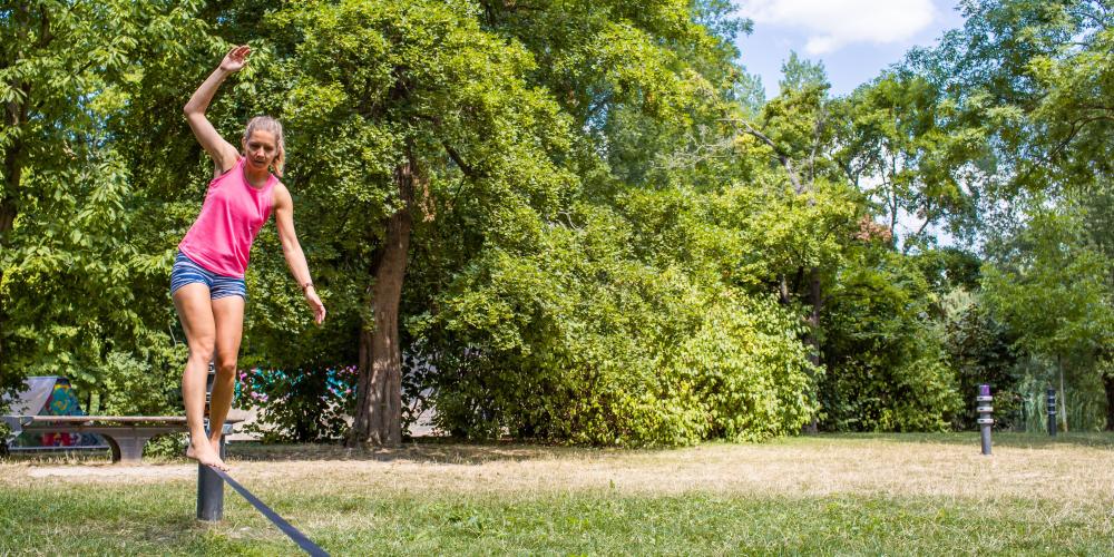 Eine Frau balanciert auf einer Slackline